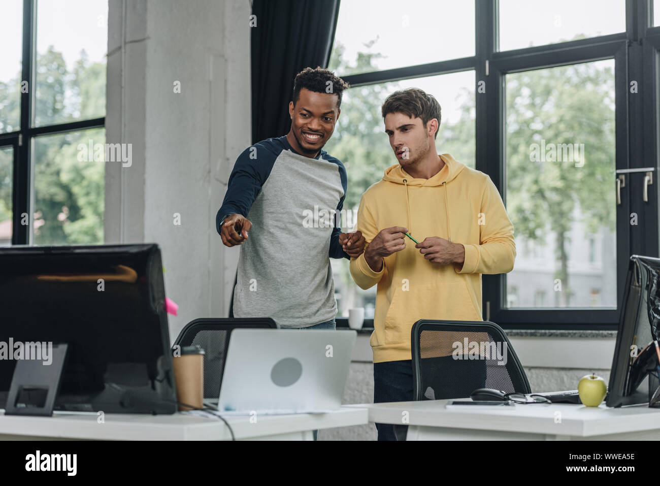 cheerful african american programmer pointing with finger at computer ...