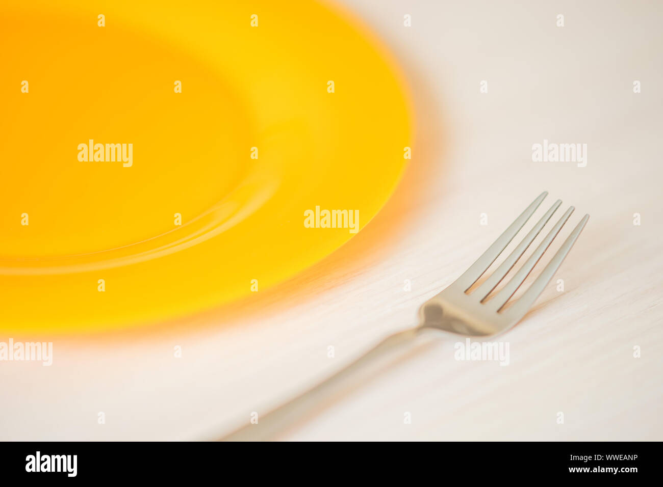 https://c8.alamy.com/comp/WWEANP/orange-plate-and-fork-closeup-on-the-light-wooden-table-WWEANP.jpg