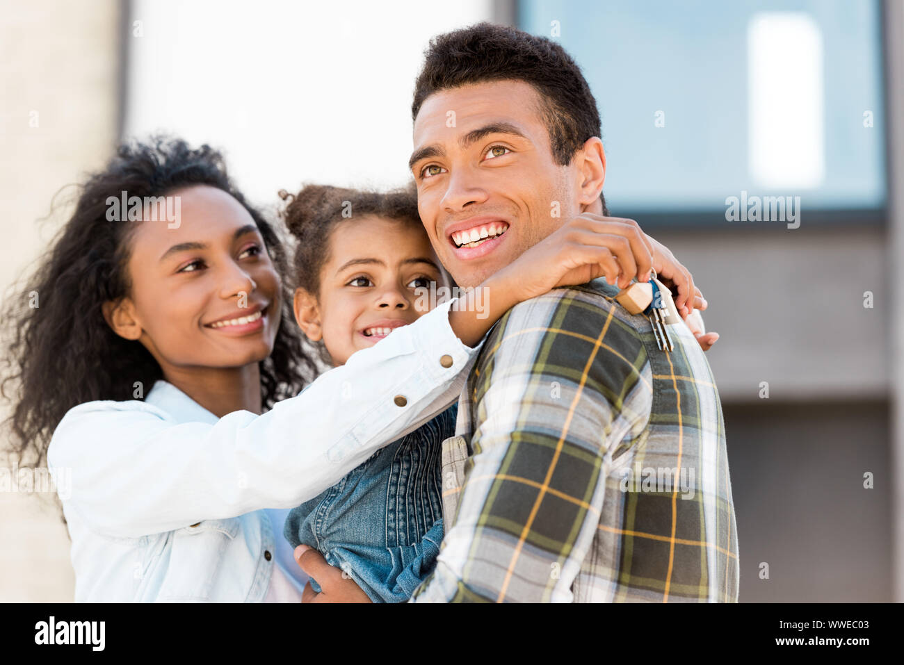 family hugging and looking away while african american woman holding ...