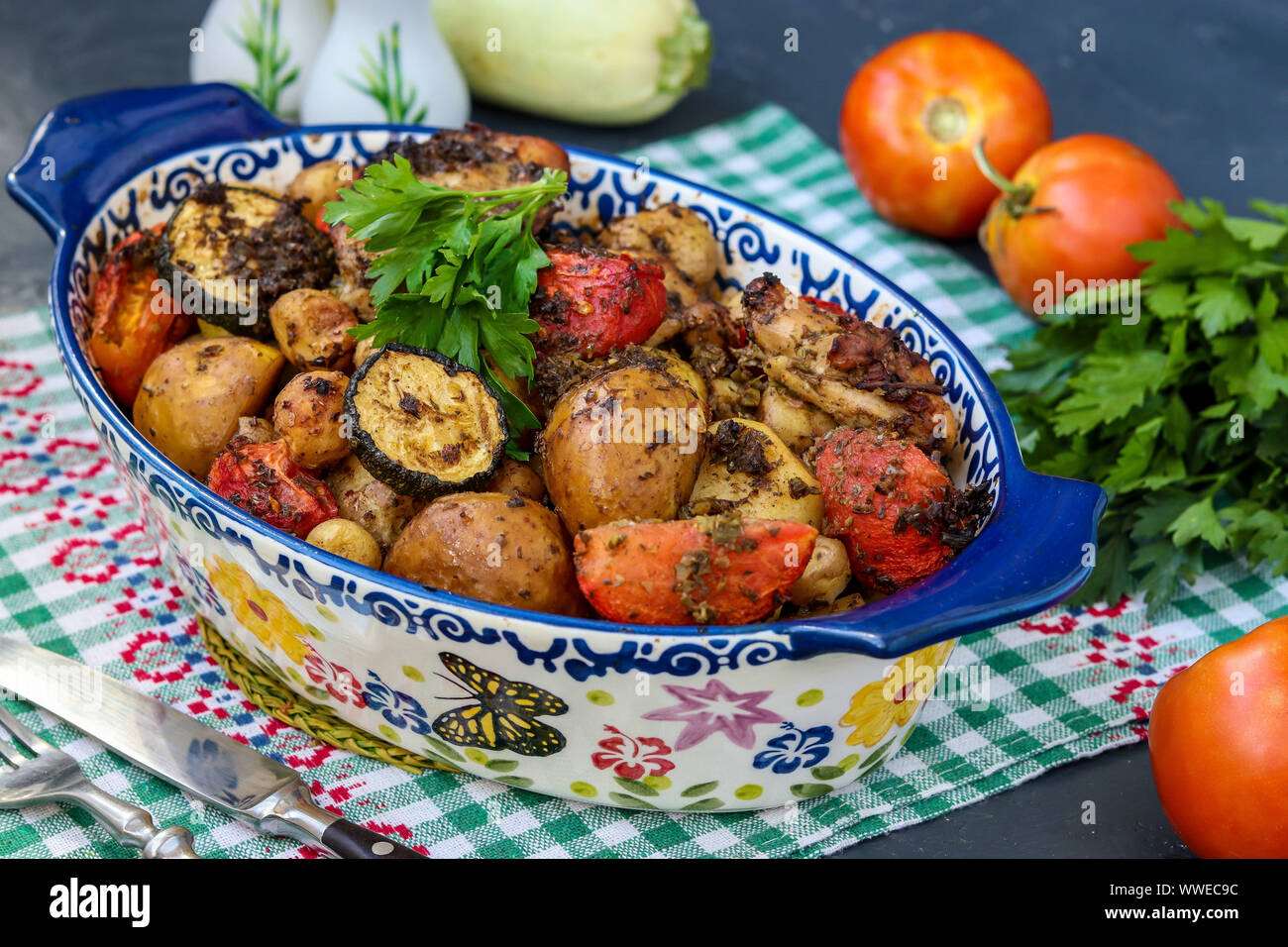 Chicken thighs baked with potatoes, tomatoes and zucchini, located in