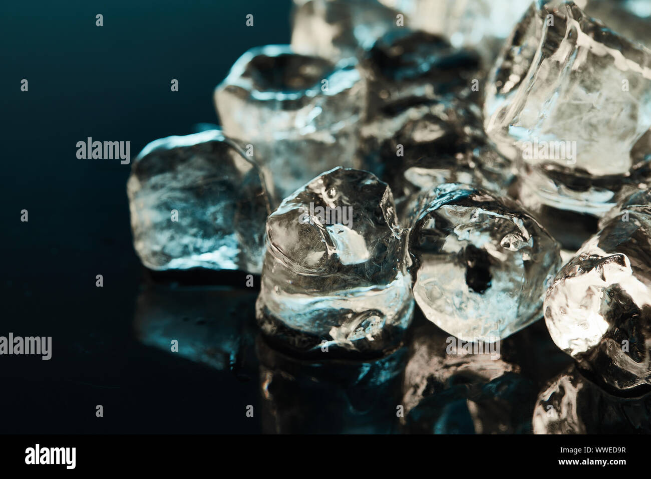 close up view of stack of transparent ice cubes on emerald background ...