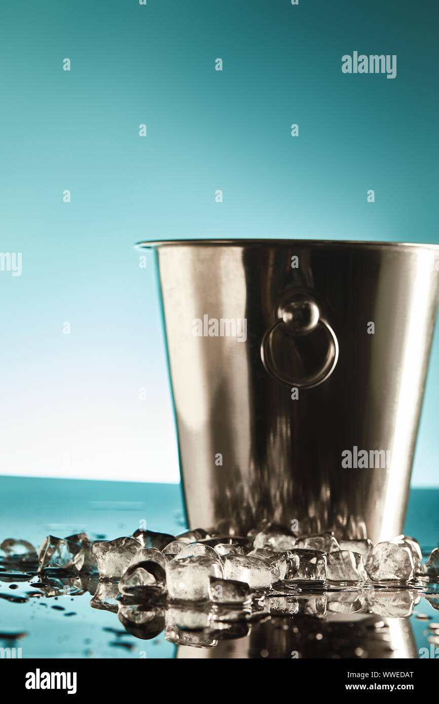 transparent ice cubes near metal bucket on emerald and white background ...