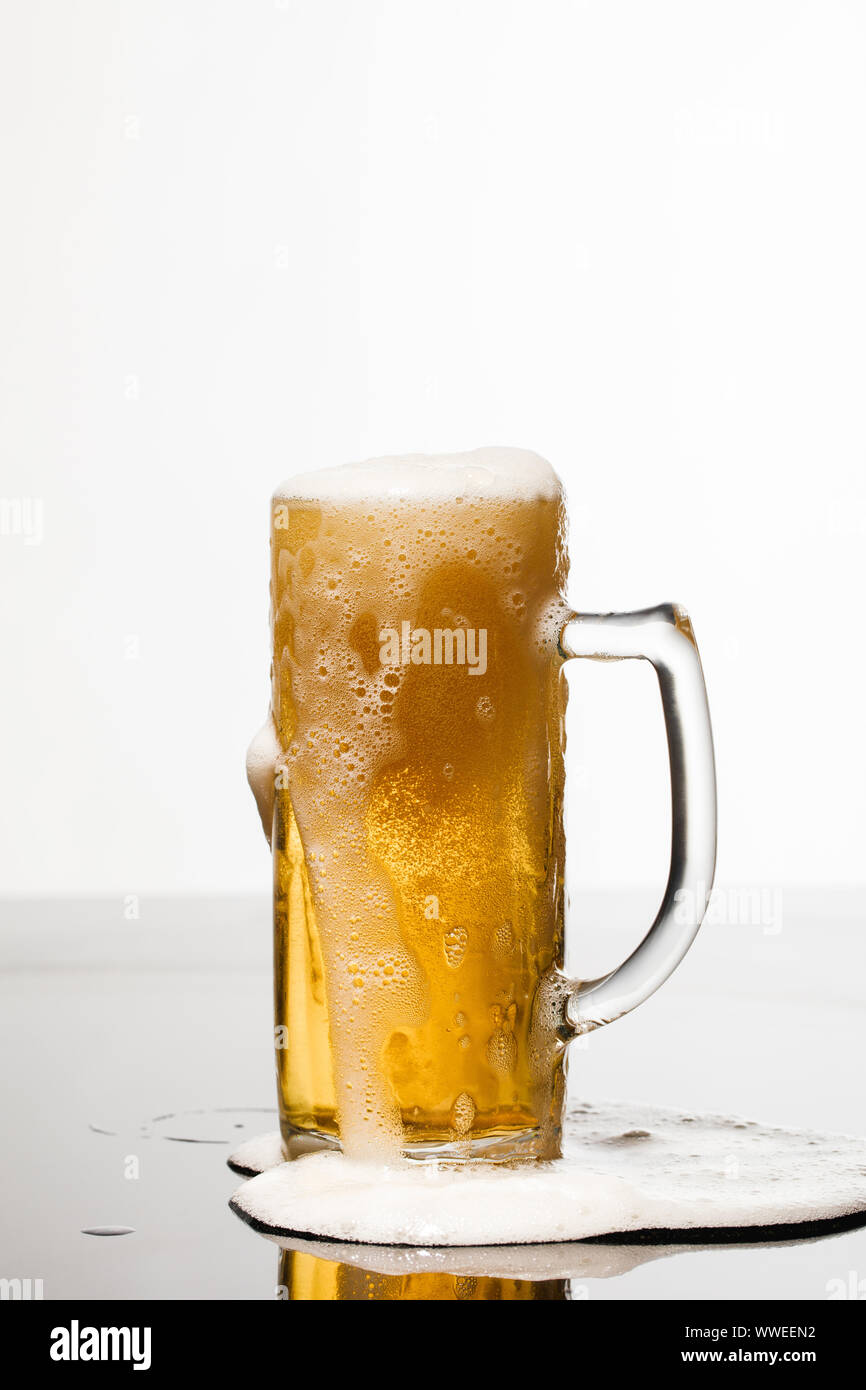 wet glass of beer with foam and puddle on surface isolated on white