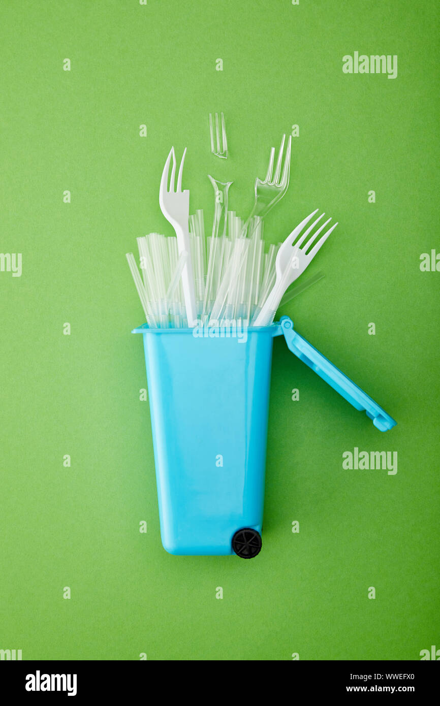 top view of blue recycle bin with broken plastic forks and straws on