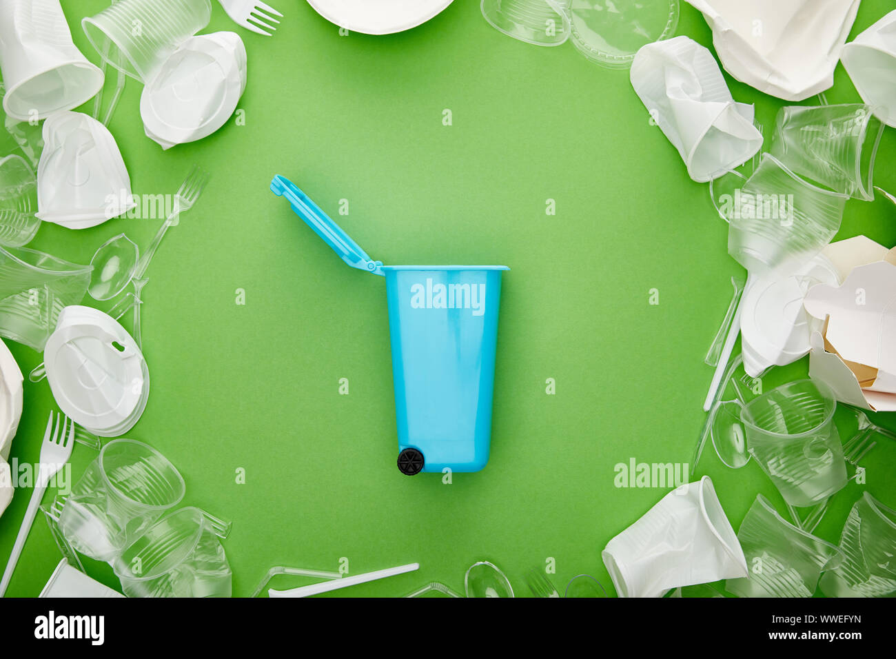 top view of blue recycle bin between crumpled plastic cups, forks