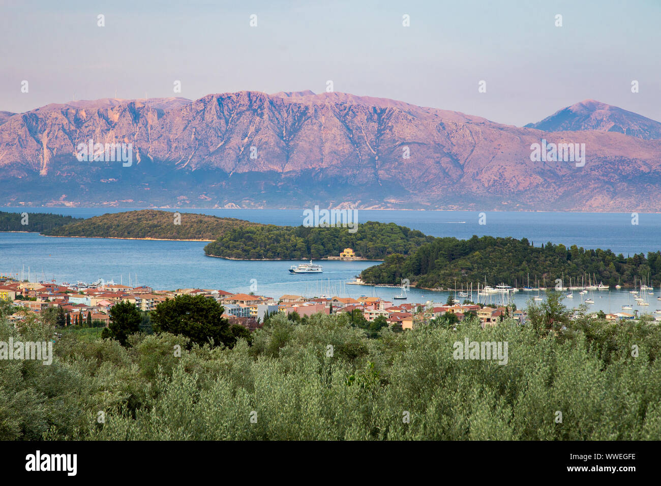 Nydri town, Madouri and Sparti islands and distant mainland mountains, Lefkada / Lefkas Island, Greece Stock Photo