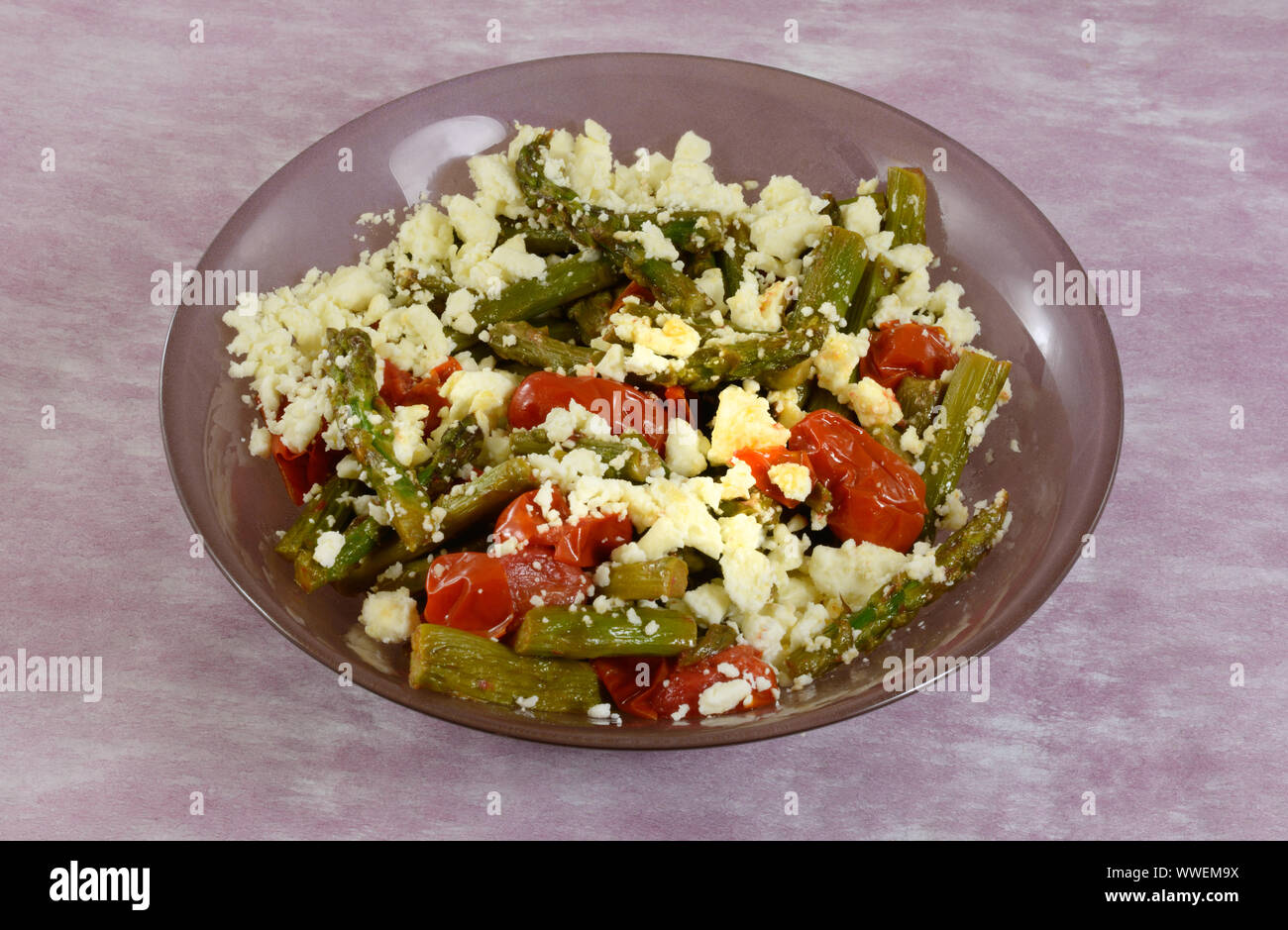 Asparagus and tomato side dish with crumbled feta cheese topping Stock Photo