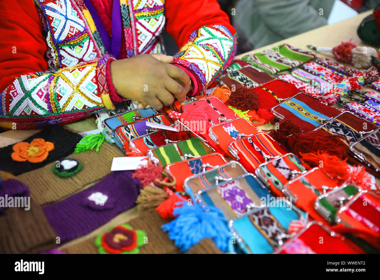 LIMA, PERU, June 23, 2019, The hands of Andean traditional woman with typical red dress sells handcraft at a market in Miraflores Stock Photo