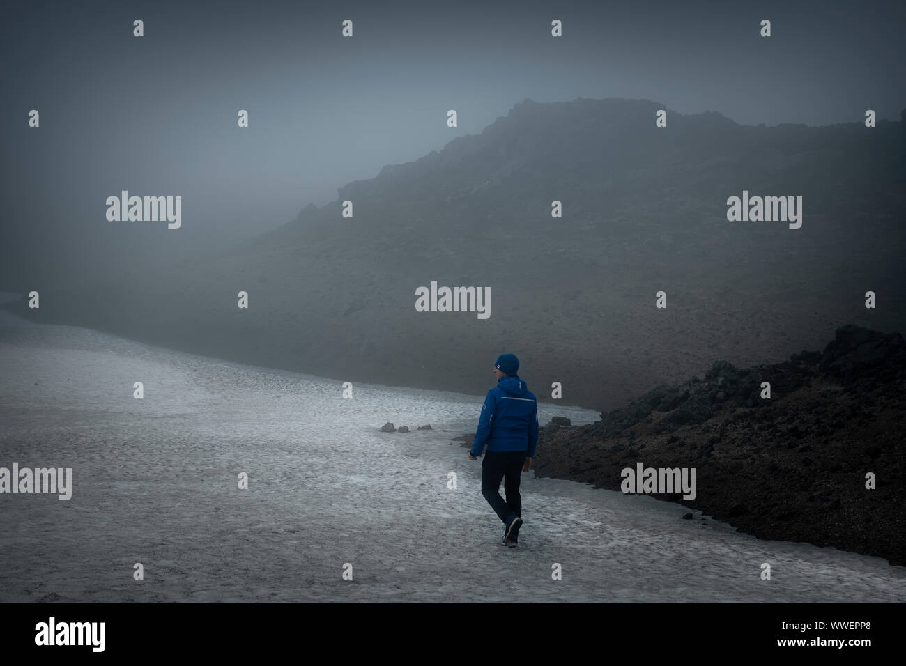 Single hiker in walking on Snaefellsjoekull glacier tongue during summer time wearing a blue jacket Stock Photo