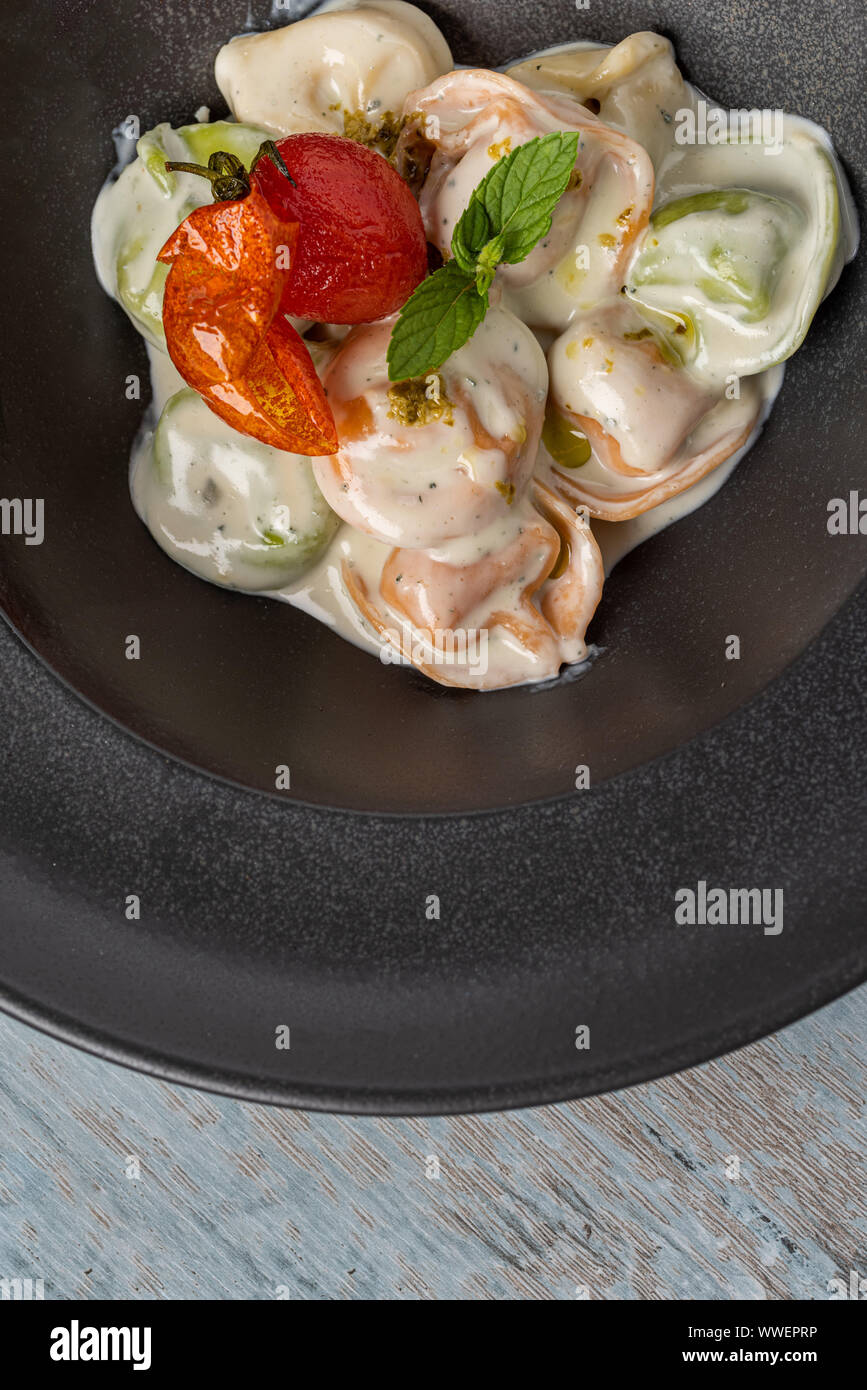 different types of pelmeni in black plate on wooden background Stock Photo