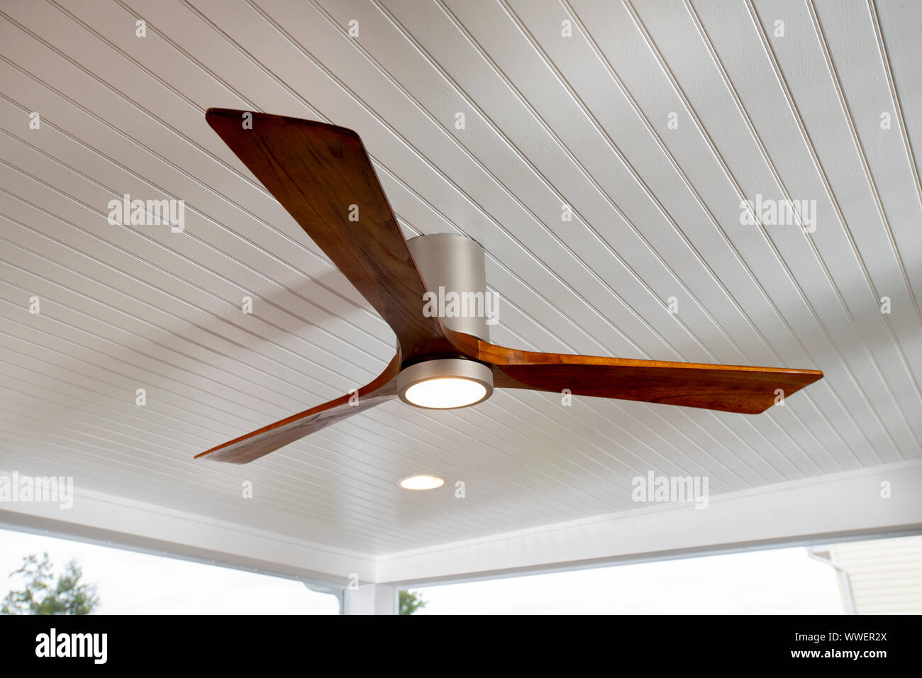 A wood three blade ceiling fan on a porch to cool the area living space Stock Photo