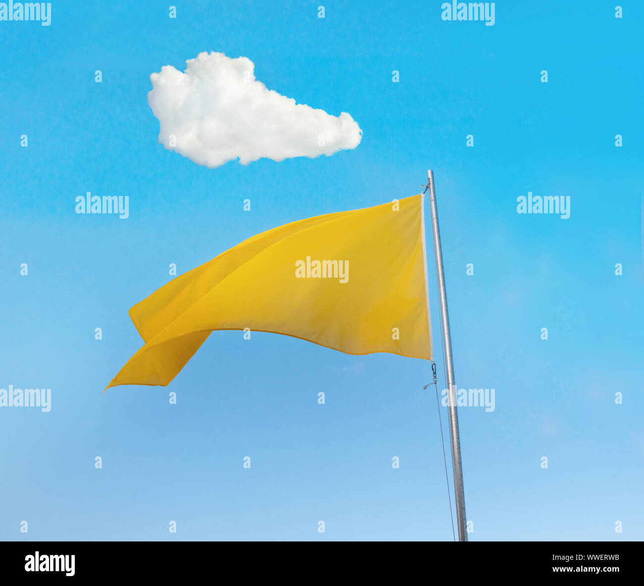 Yellow flag over blue sky with a white cloud above Stock Photo