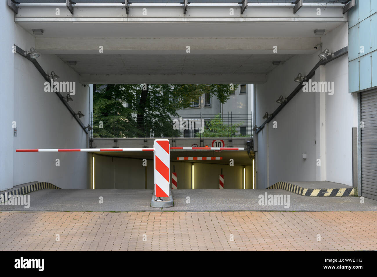 entrance and exit driveway with barrier to a underground parking garage Stock Photo