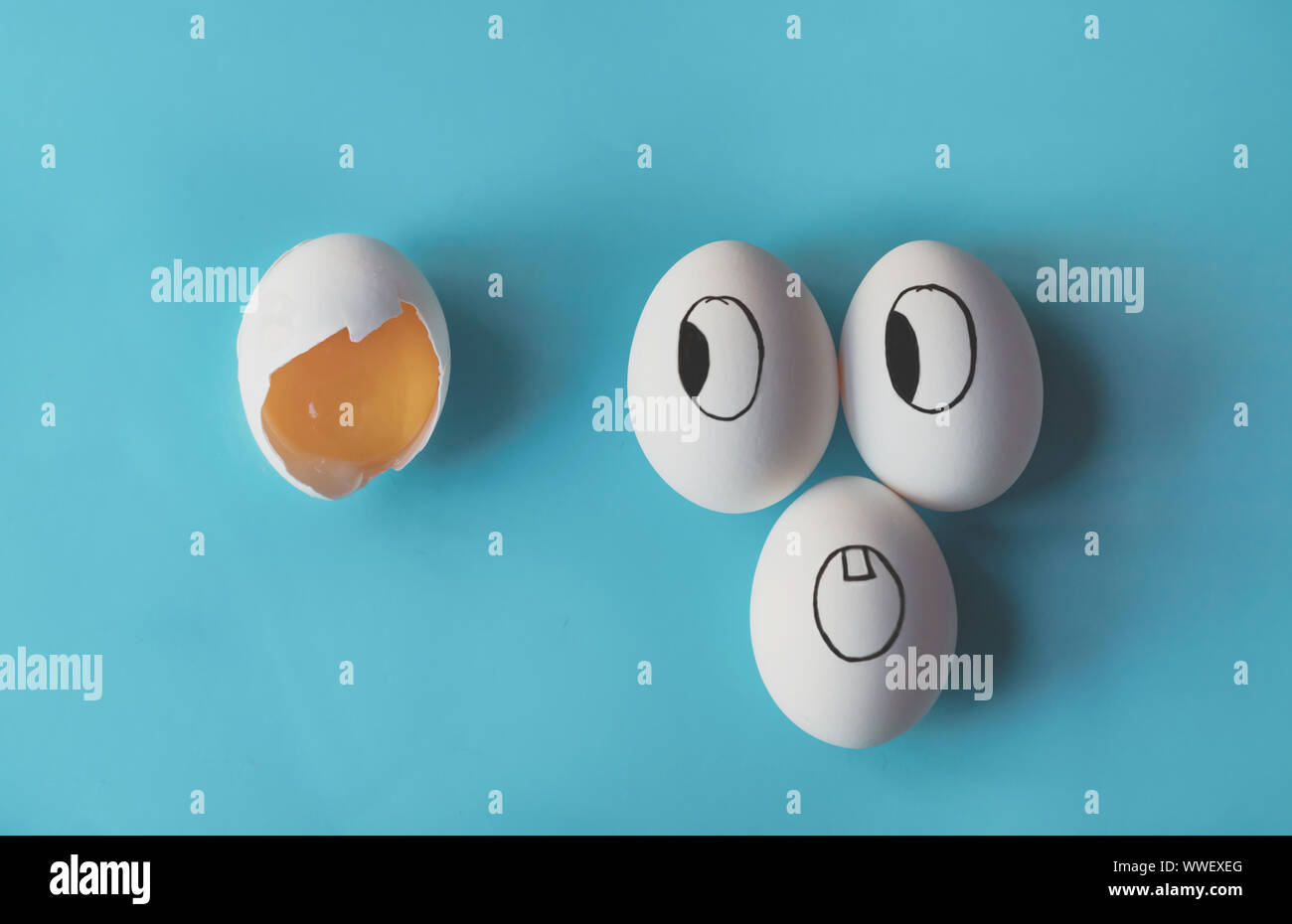 White eggs with faces painted in the shell next to a broken egg Stock