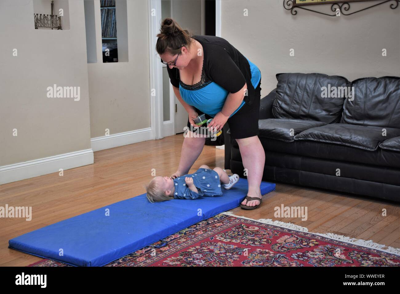 Young heavy mother with her child playing on mad in living room of home Stock Photo