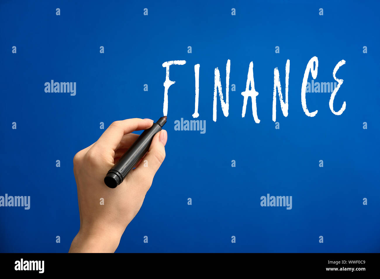 Female hand writing word FINANCE on color background Stock Photo - Alamy