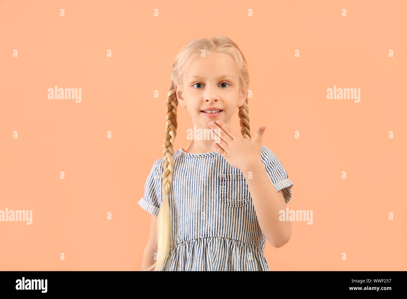 Little deaf mute girl using sign language on color background Stock