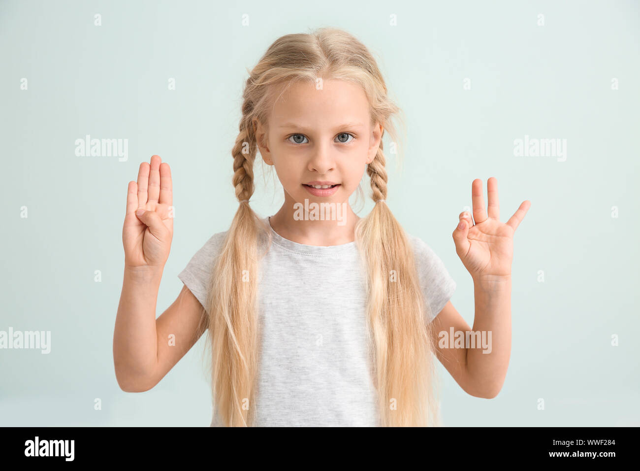 Little deaf mute girl using sign language on light background Stock Photo -  Alamy