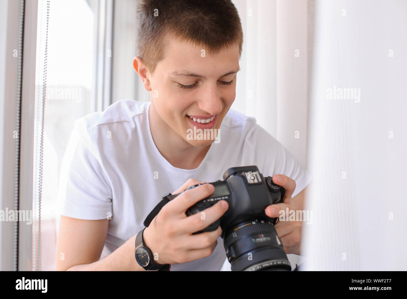 Teenage boy with photo camera near window Stock Photo Alamy
