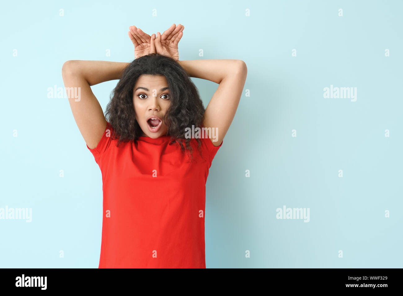 Portrait of shocked African-American woman on color background Stock ...