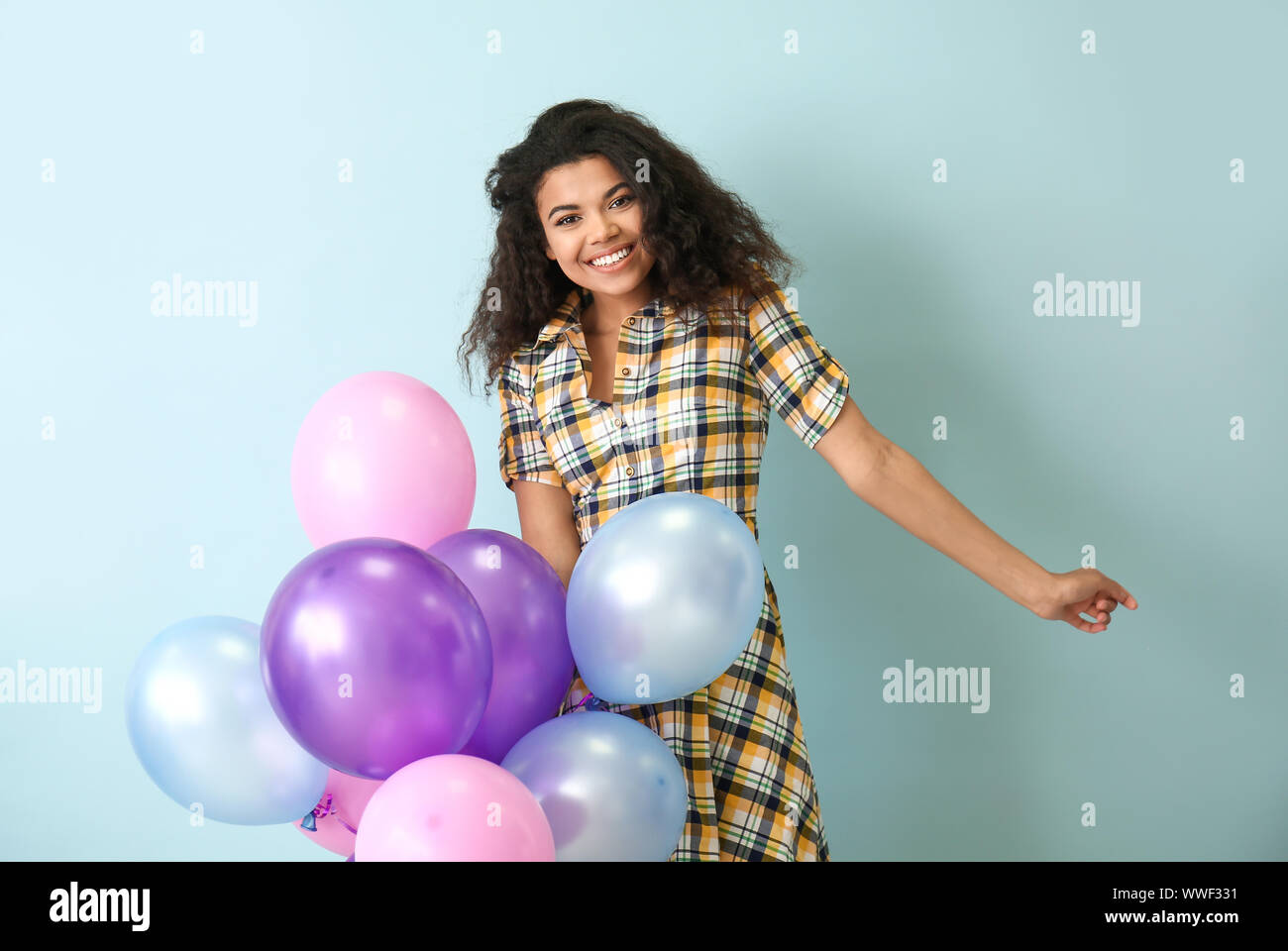 Portrait of happy African-American woman with air balloons on color ...