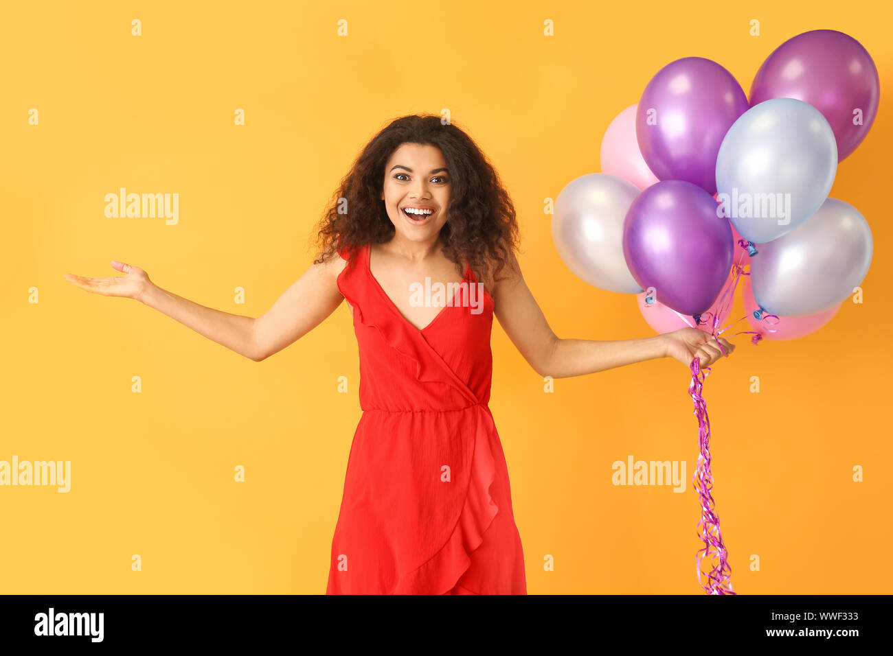 Portrait of happy African-American woman with air balloons on color ...