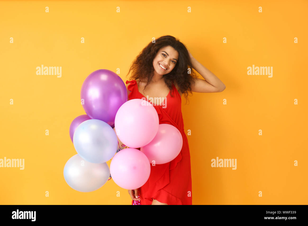 Portrait of happy African-American woman with air balloons on color ...