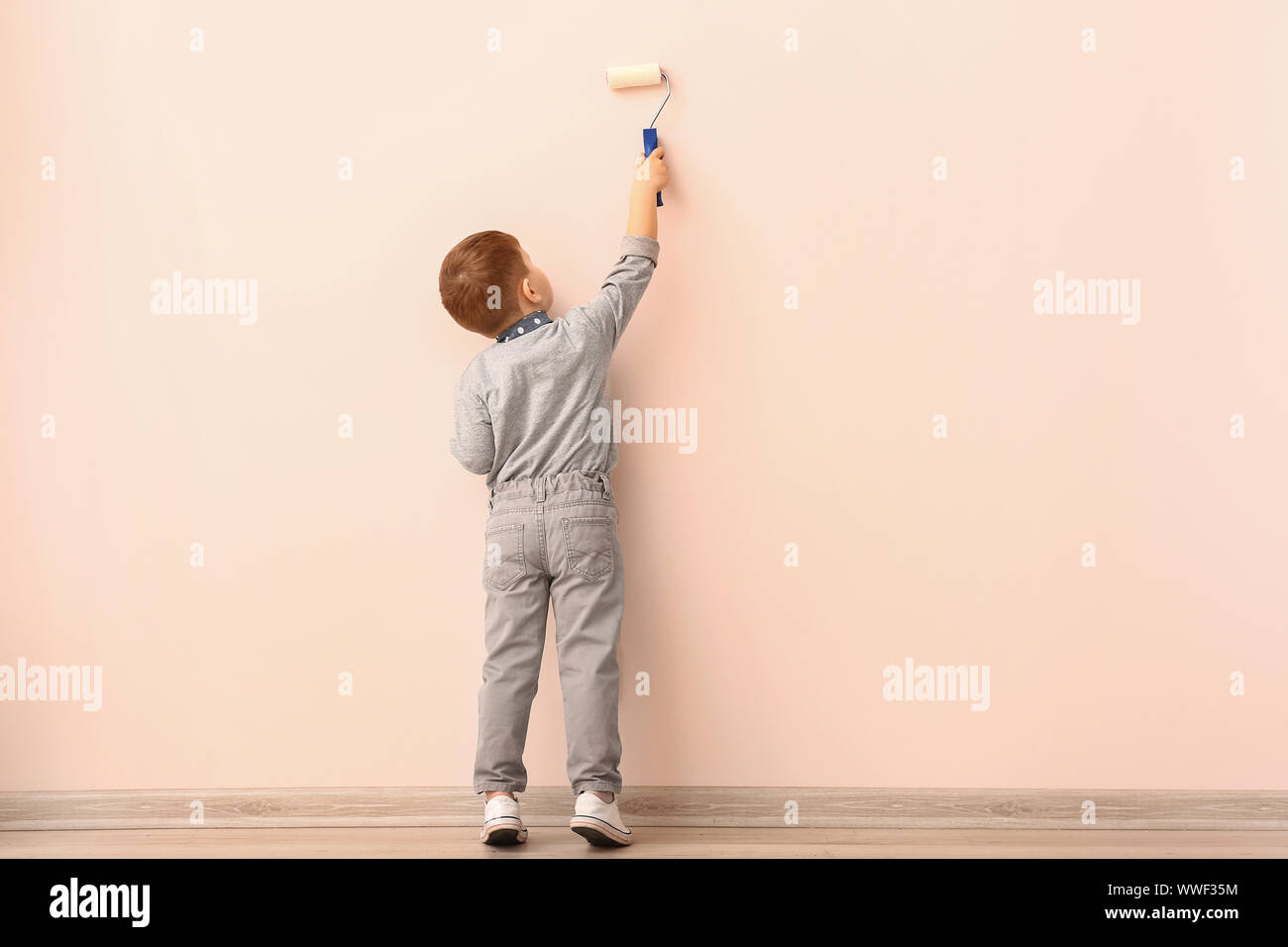 Cute little boy painting wall in room Stock Photo Alamy