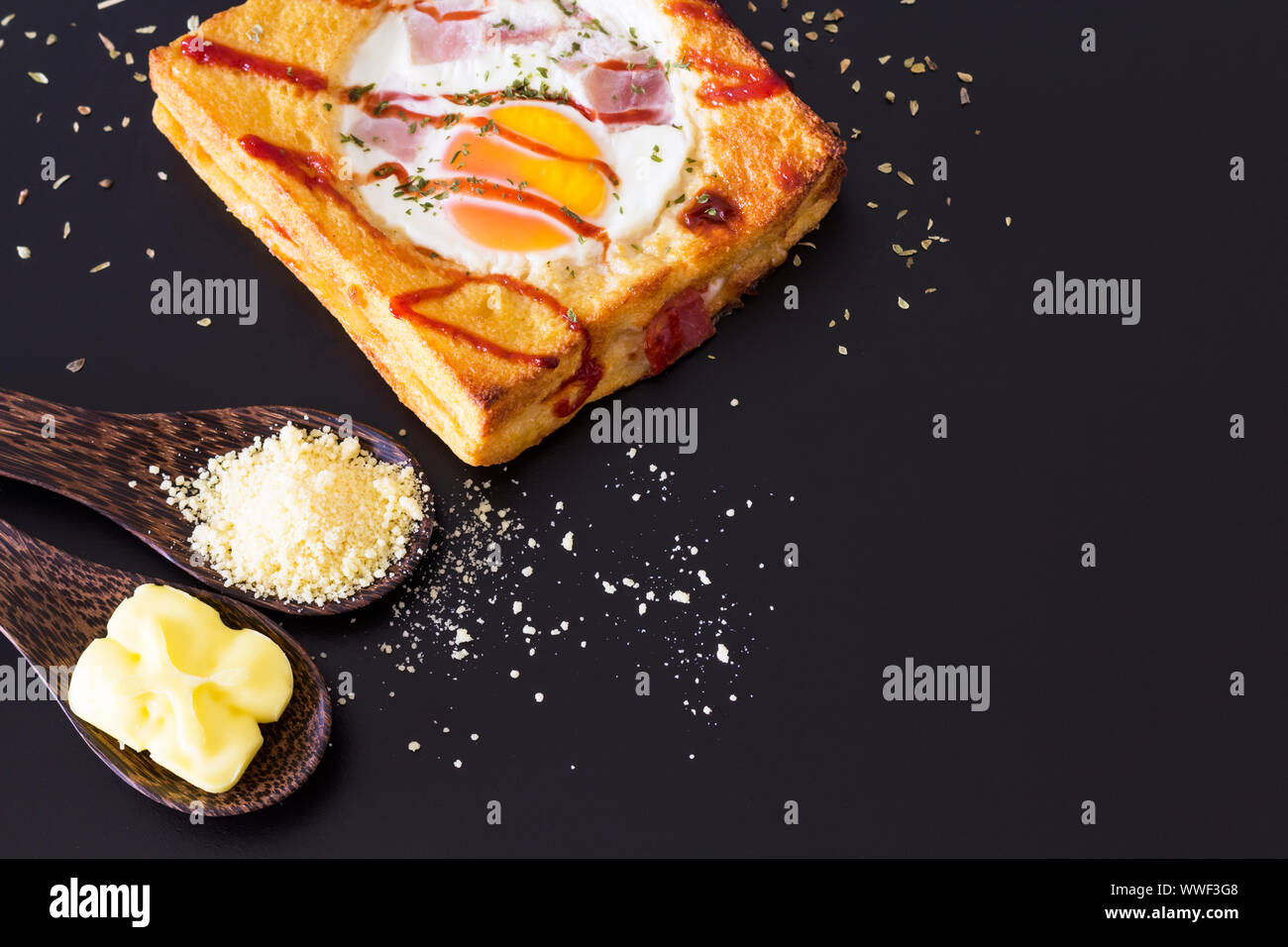 Baked bread and egg on black background, selective focus Stock Photo