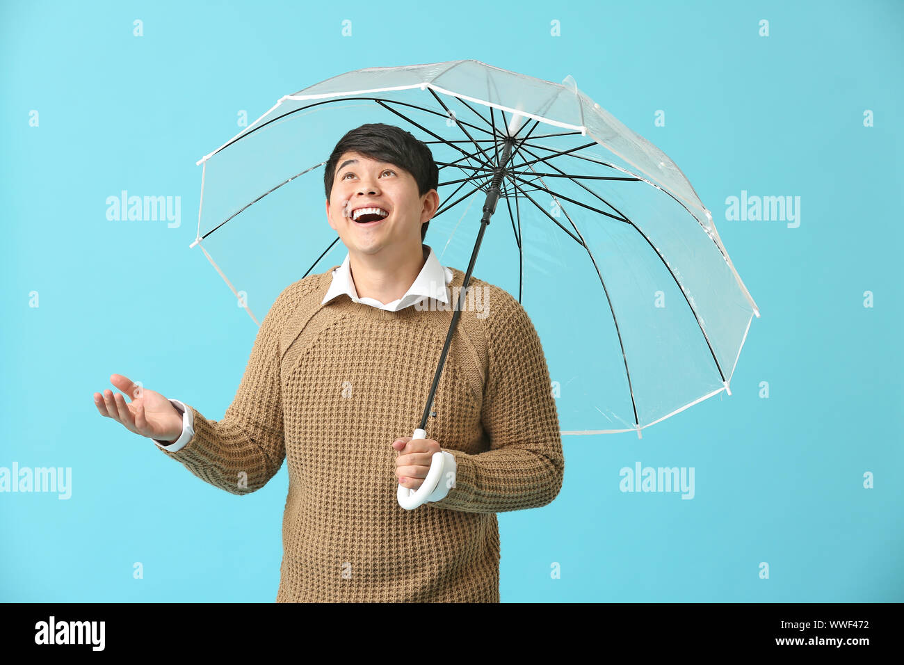 Handsome Asian man with umbrella on color background Stock Photo - Alamy