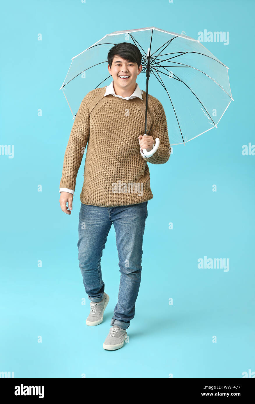 Handsome Asian man with umbrella on color background Stock Photo - Alamy