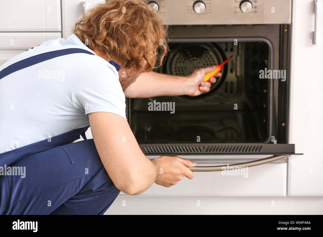 Worker repairing oven in kitchen Stock Photo Alamy
