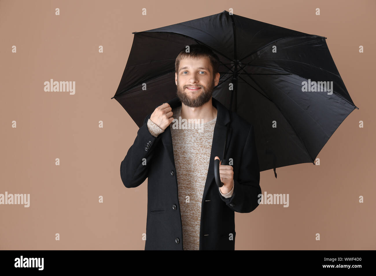 Handsome man with umbrella on color background Stock Photo - Alamy