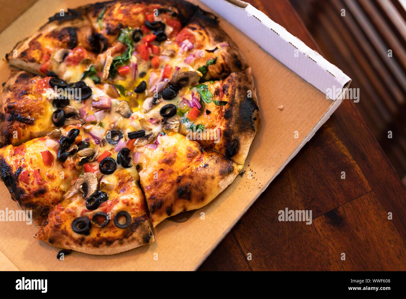 enjoyable healthy food concept, vegetarian woodfire pizza in cardboard box on wooden table ...