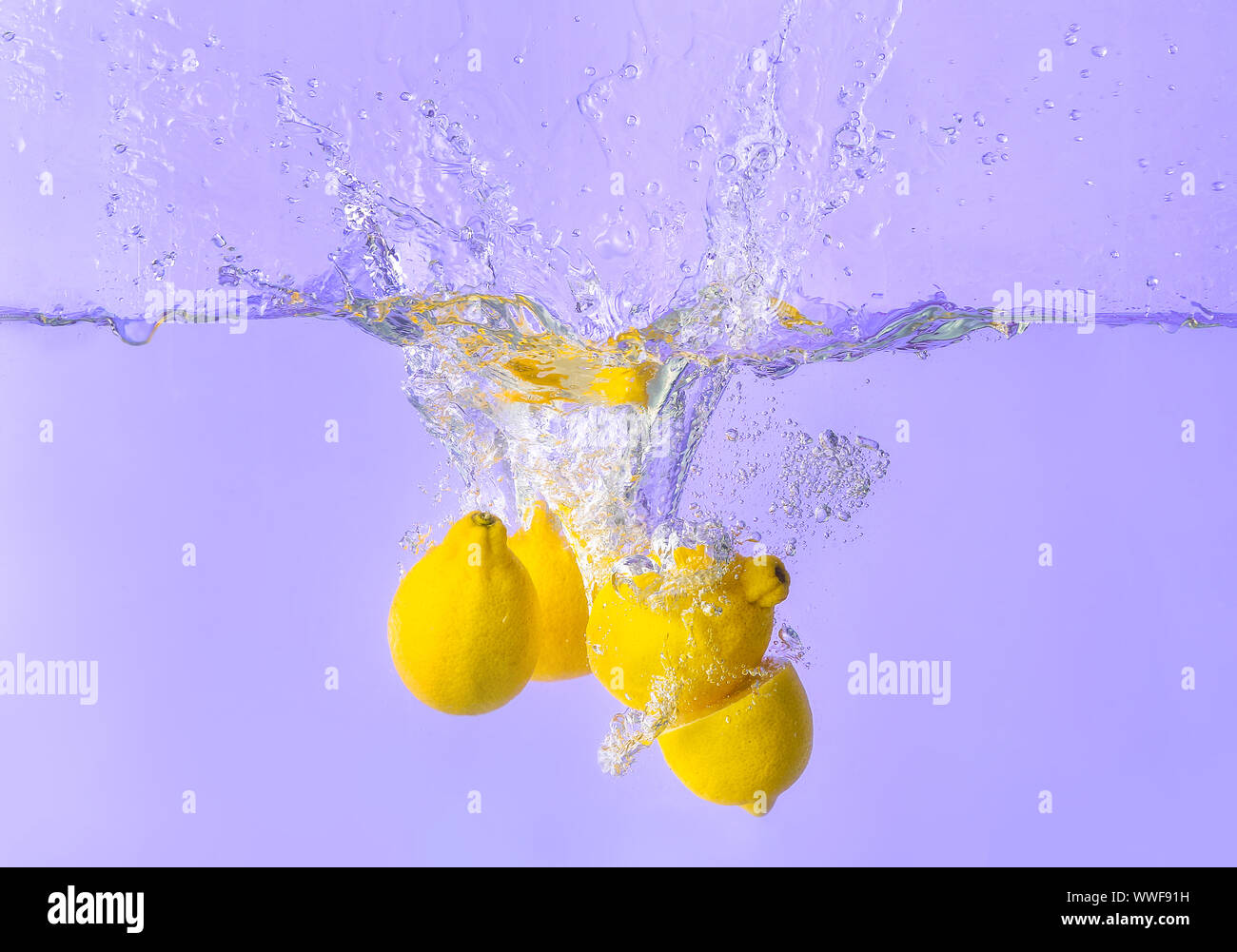 Falling of lemons into water on color background Stock Photo Alamy