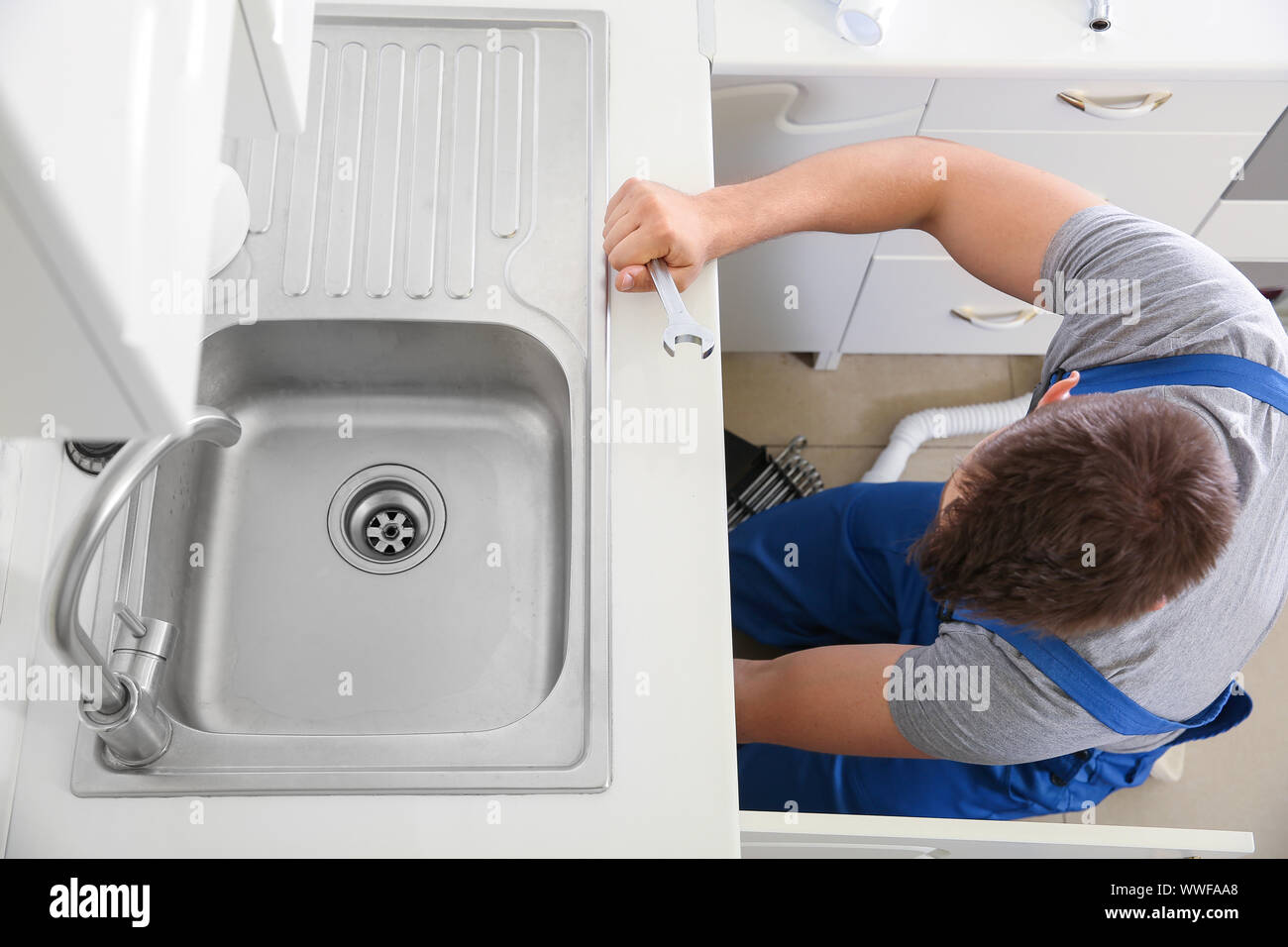 Plumber installing sink in kitchen Stock Photo Alamy