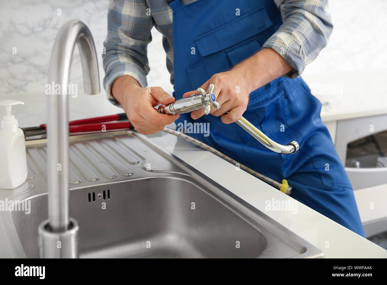 Plumber installing sink in kitchen Stock Photo Alamy