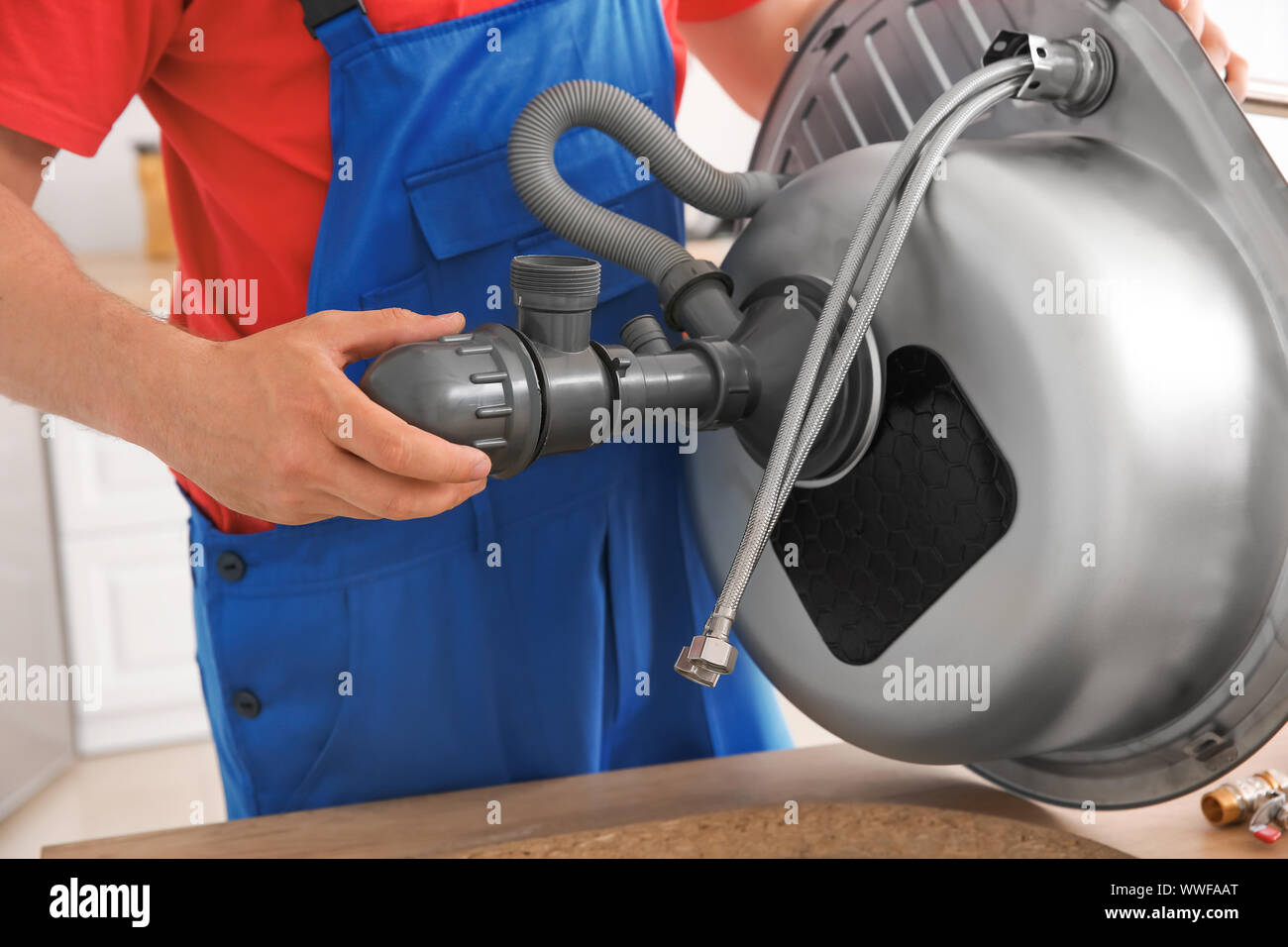 Plumber installing sink in kitchen Stock Photo Alamy