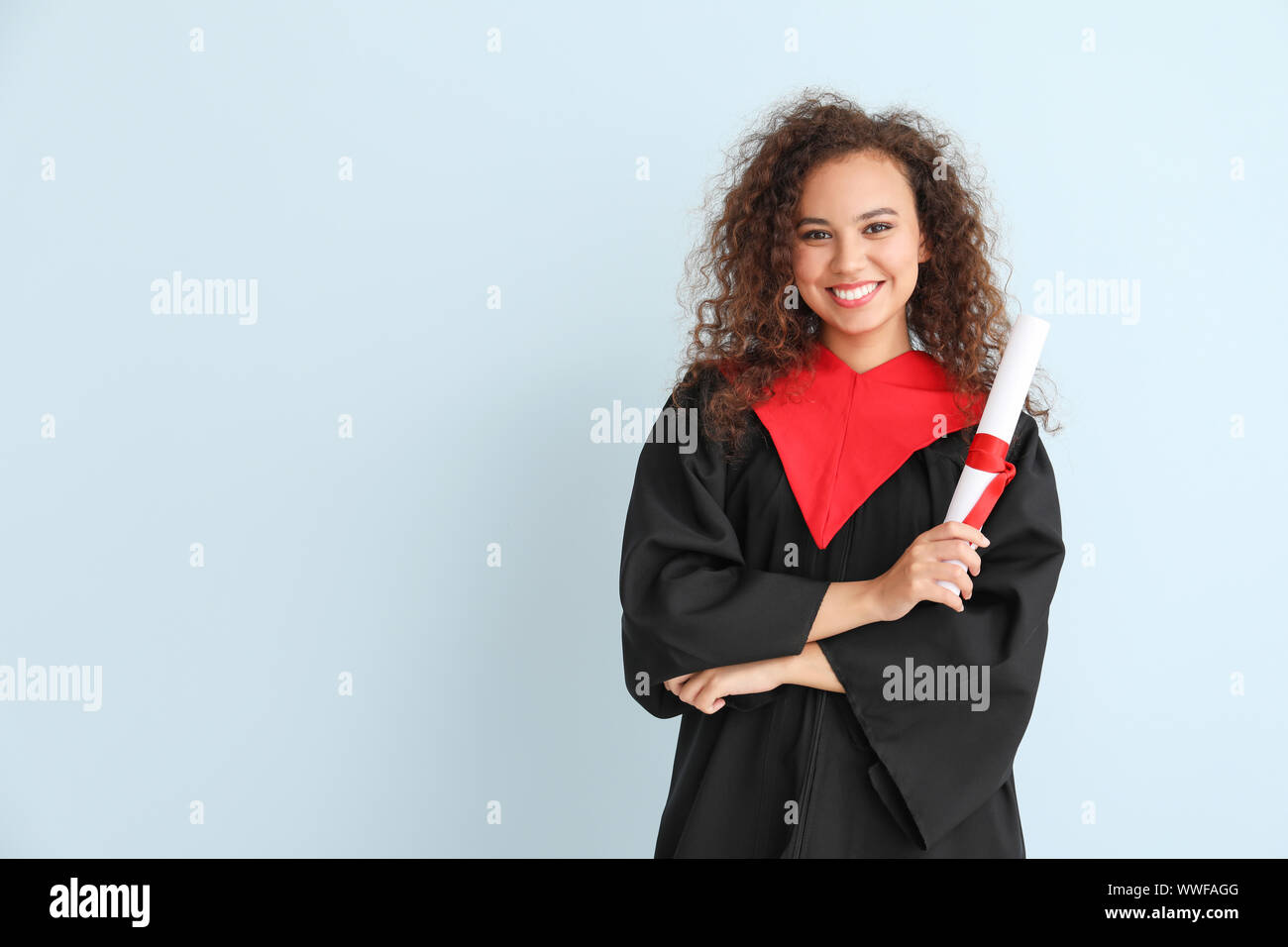 Young African-American student in bachelor robe and with diploma on ...