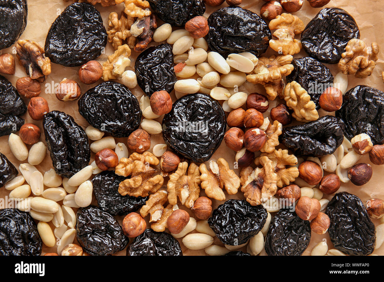 Tasty prunes with nuts on parchment, top view Stock Photo