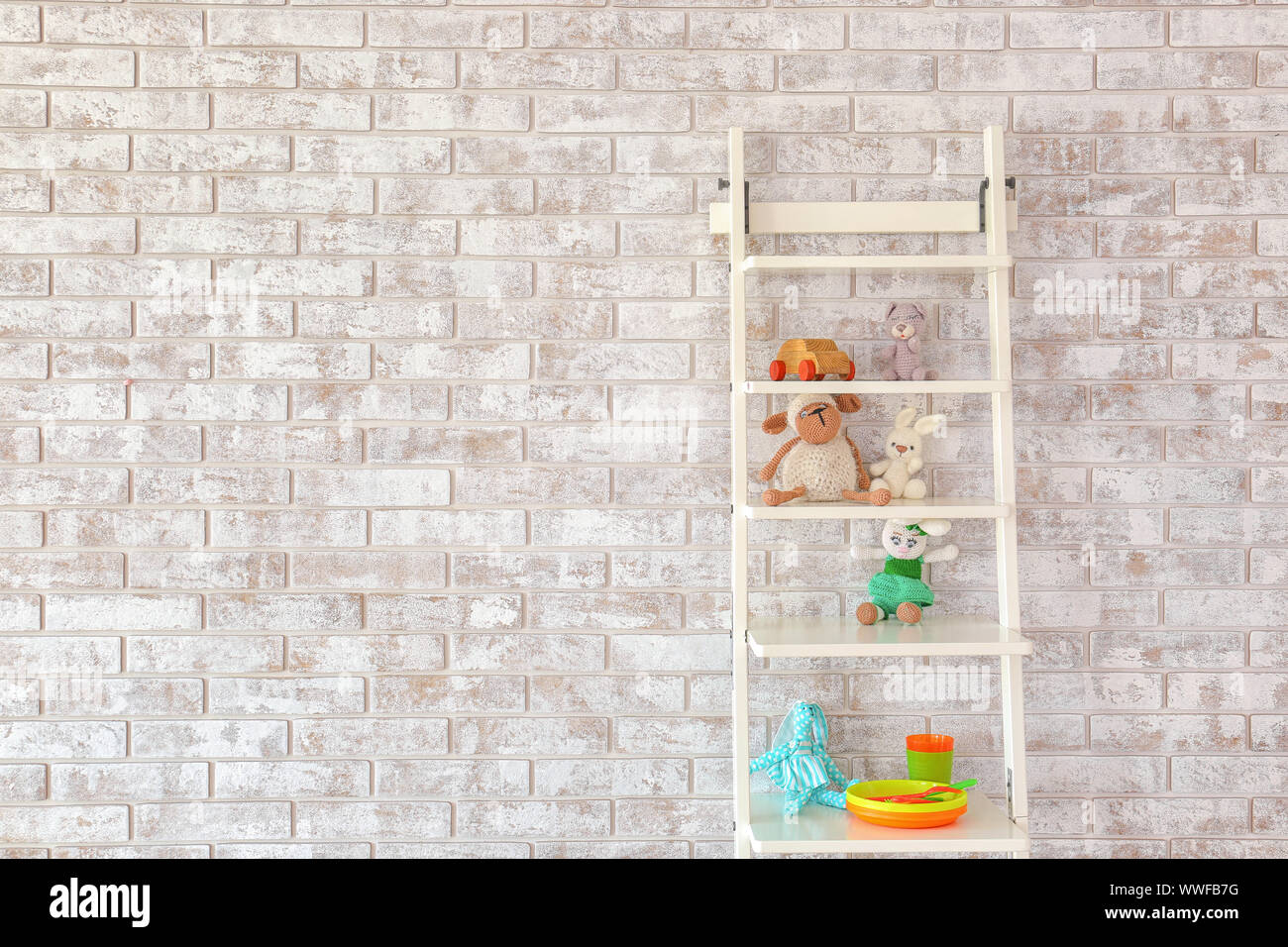 Rack with toys near brick wall in children's room Stock Photo - Alamy