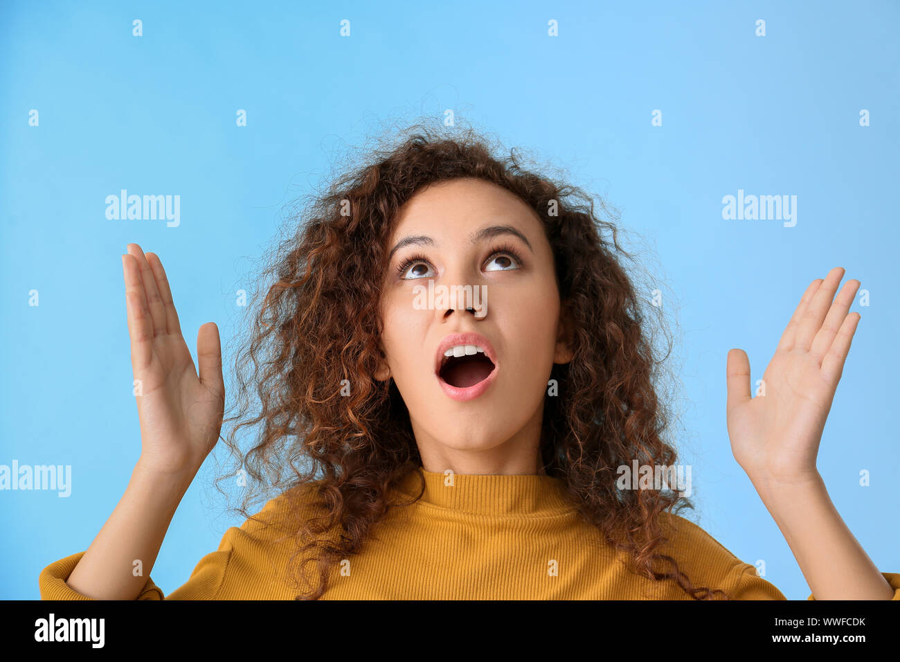 Shocked African-American woman on color background Stock Photo - Alamy