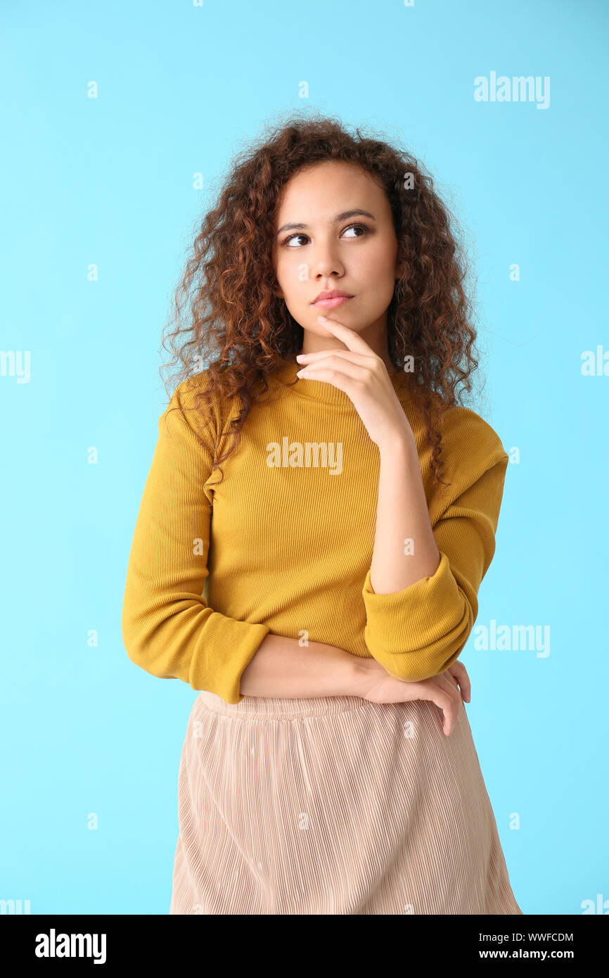 Thoughtful African-American woman on color background Stock Photo - Alamy