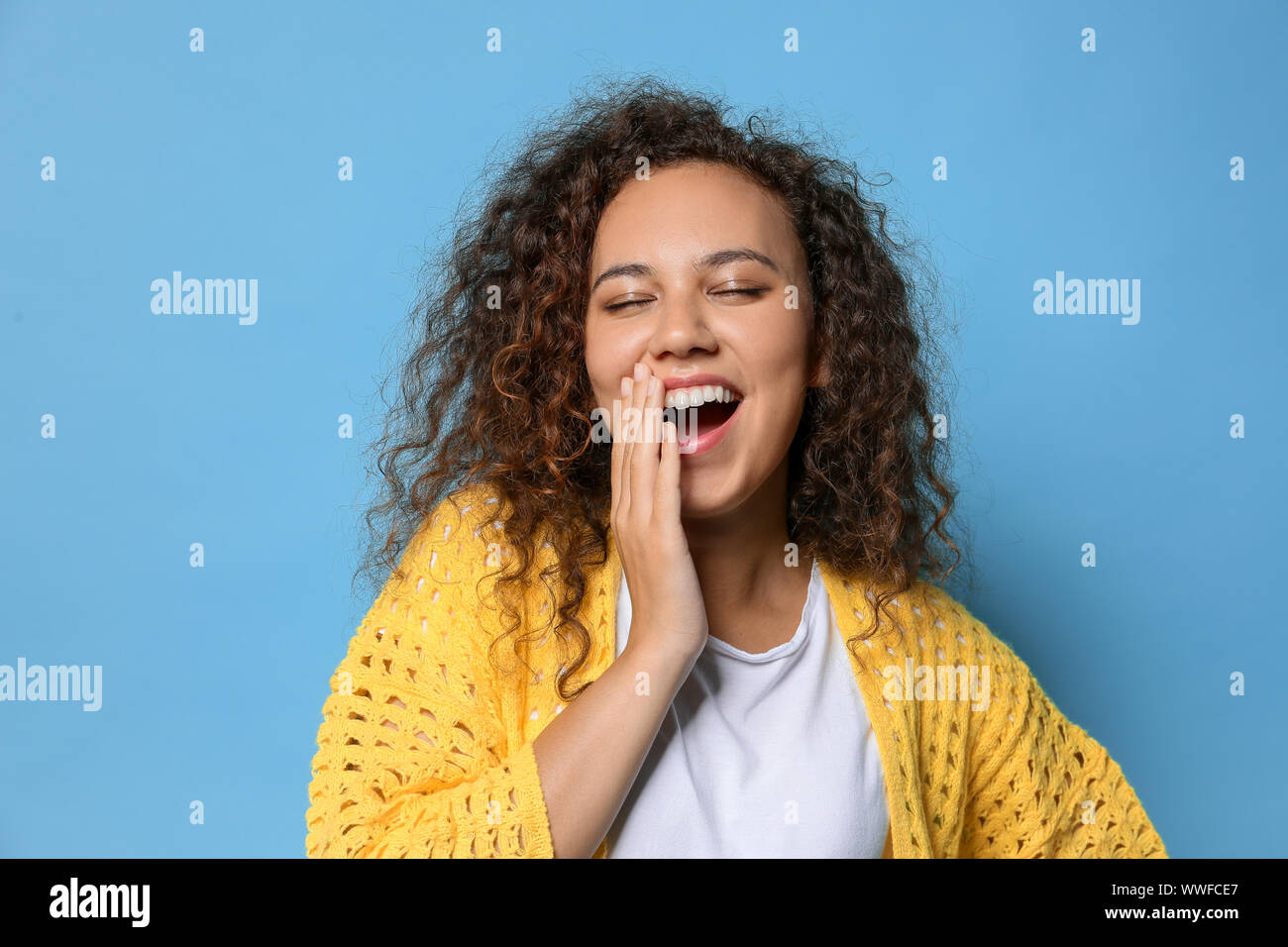 Happy yawning African-American woman on color background Stock Photo ...