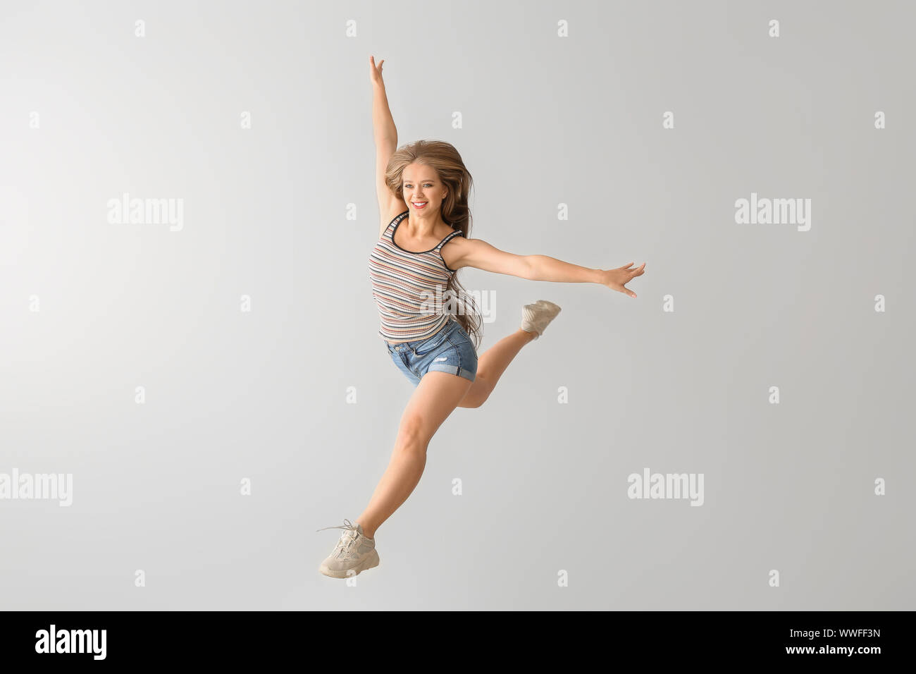 Jumping young woman against white background Stock Photo - Alamy