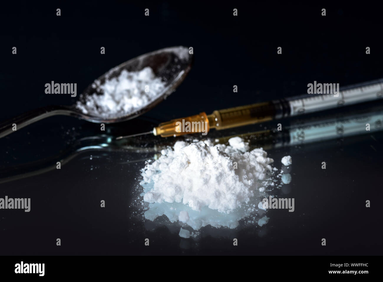 White powder, syringe and drug on spoon. Narcotic addiction concept. Black mirror background Stock Photo