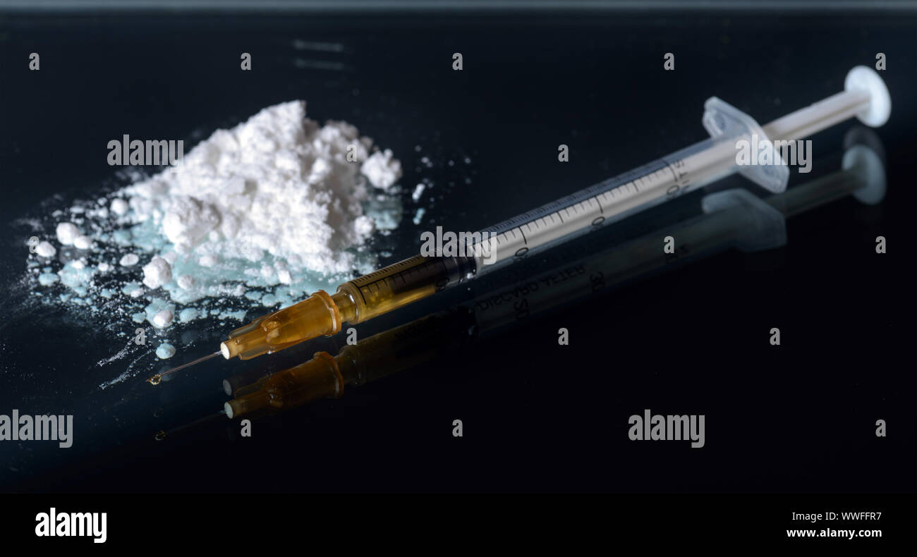 White powder drag and syringe. Narcotic addiction concept Narcotic addiction concept. Black mirror background Stock Photo