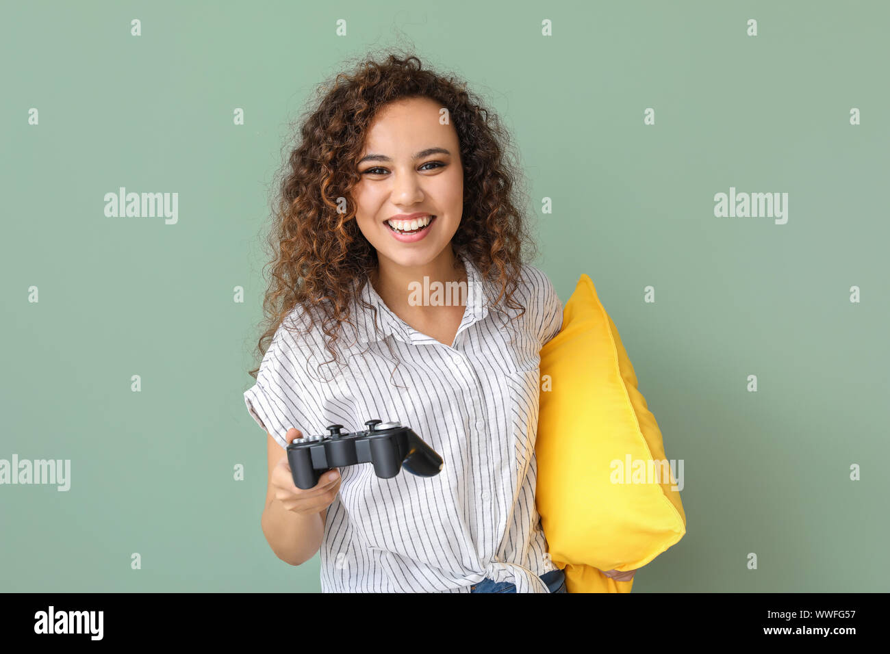 African-American teenage girl playing video game on color background ...