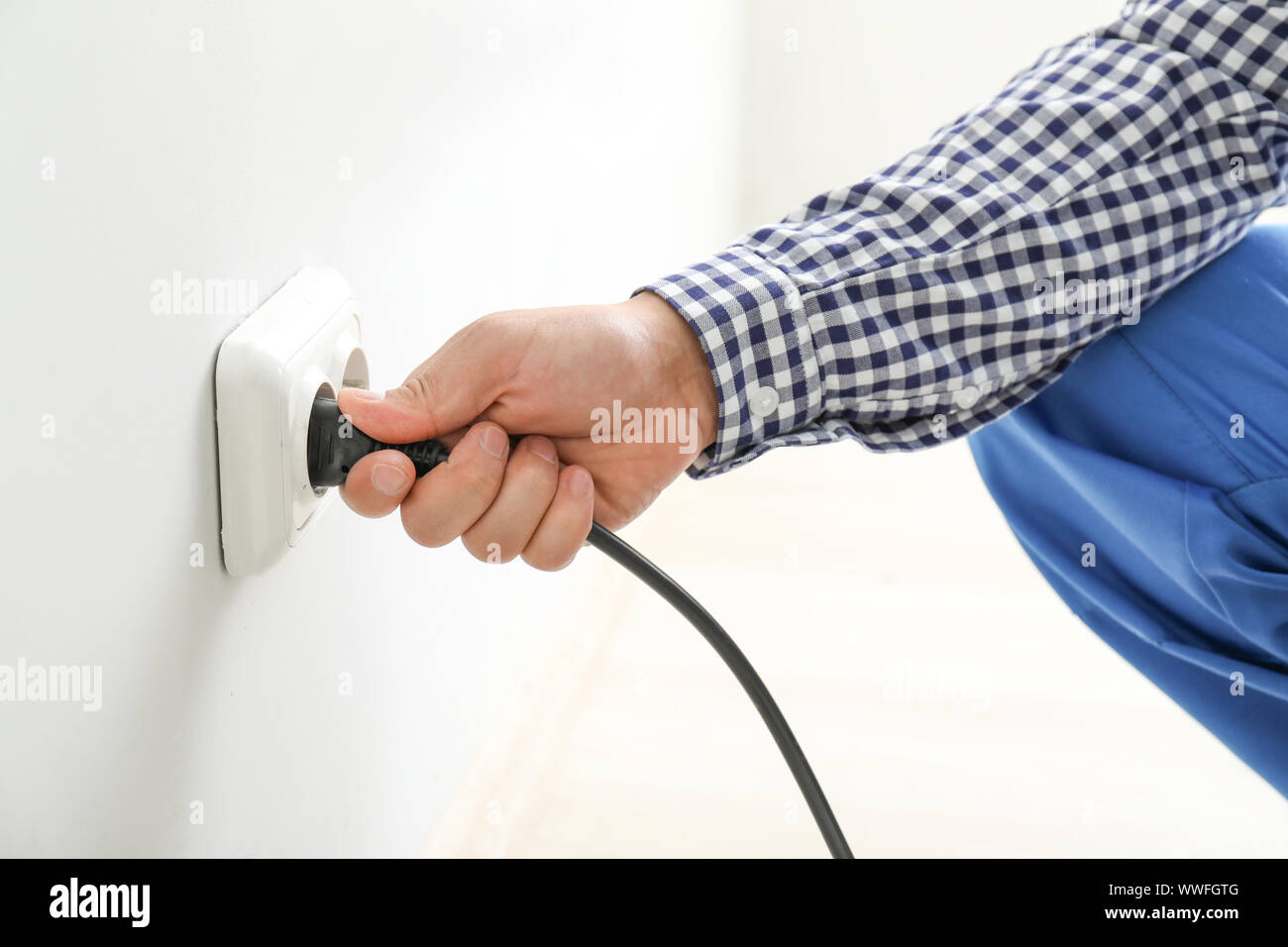 Electrician inserting plug in socket, closeup Stock Photo