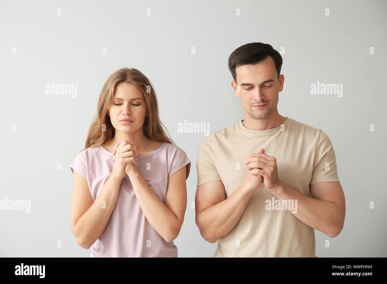 Religious couple praying to God on light background Stock Photo Alamy